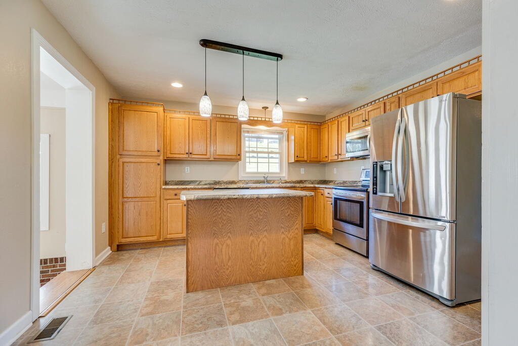 Kitchen with a wood island, honey-toned cabinets, and stainless steel appliances.