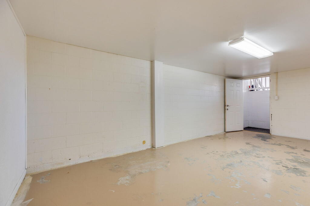Empty unfinished room with painted block walls, a worn concrete floor, and an open door.