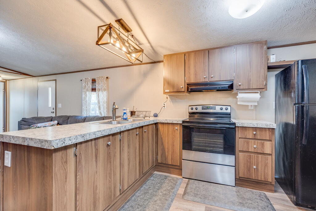 Kitchen with wood-tone cabinets, stone-look counters, stainless steel appliances, and a peninsula.