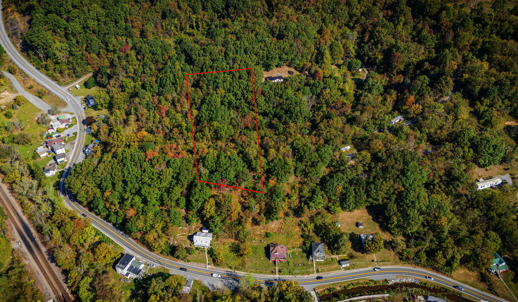 Wooded parcel outlined in red among autumn trees, with a curving road and nearby homes.