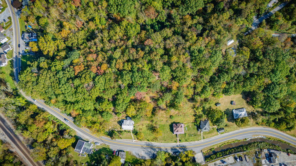 Aerial view of wooded land and a clearing beside a curving road.
