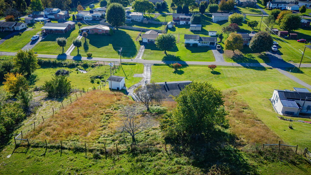 Aerial view of a grassy, partly fenced lot among neighboring homes.