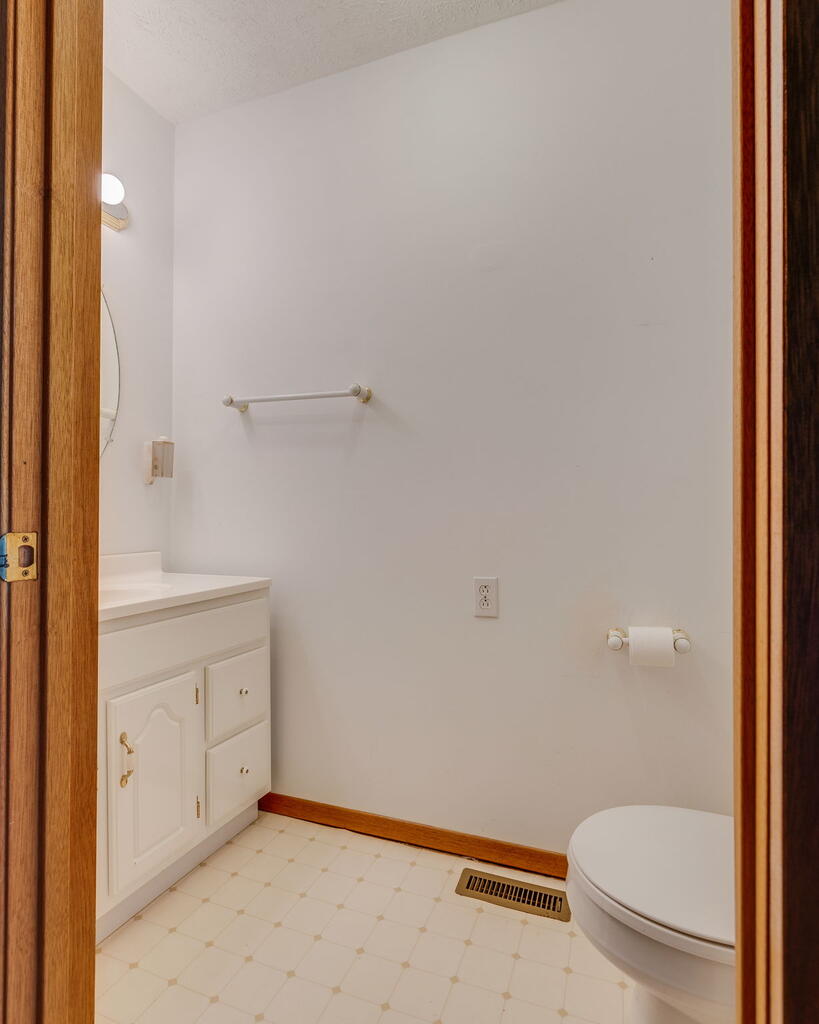 Bathroom with a white vanity, toilet, and light patterned tile floor.