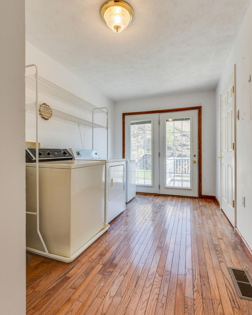 Laundry room with washer and dryer, wire shelving, hardwood floors, and glass doors to a deck.