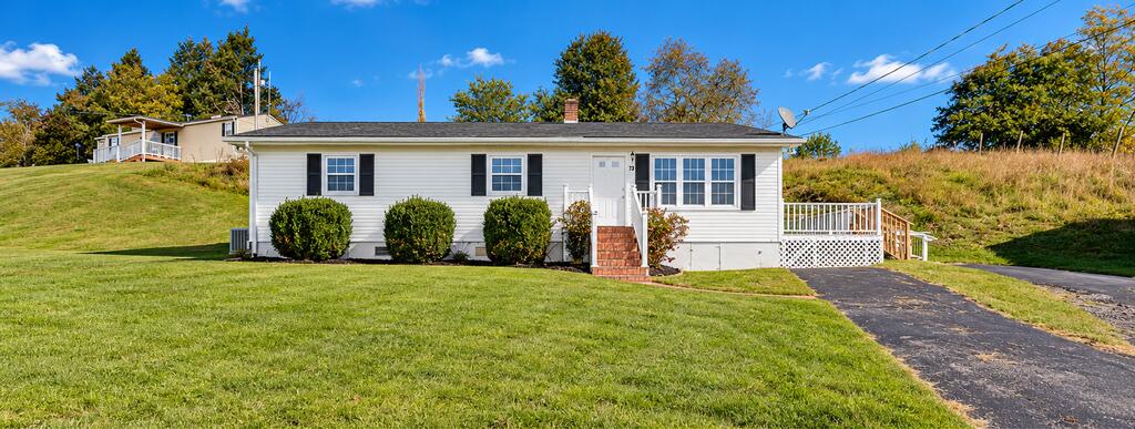 Single-story white home with black shutters, front lawn, and paved driveway.