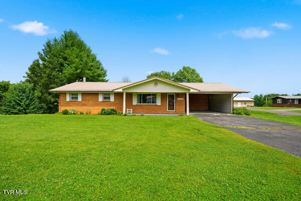 Single-story brick ranch with a covered carport and broad green lawn.