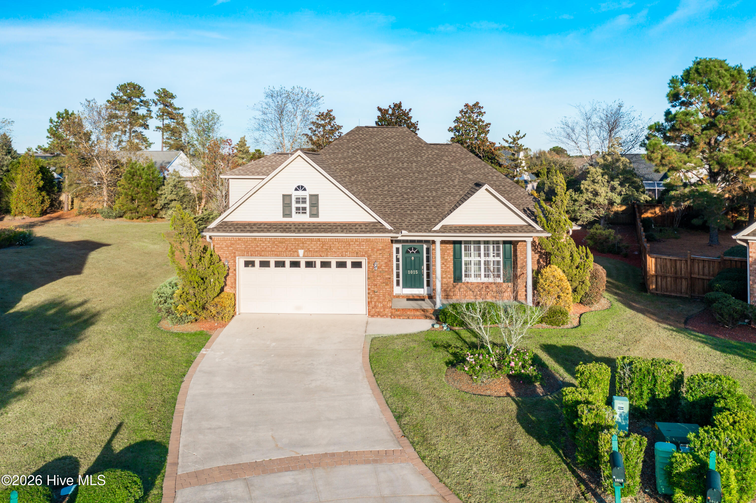 Brick house with green shutters, a two-car garage, and a wide driveway.
