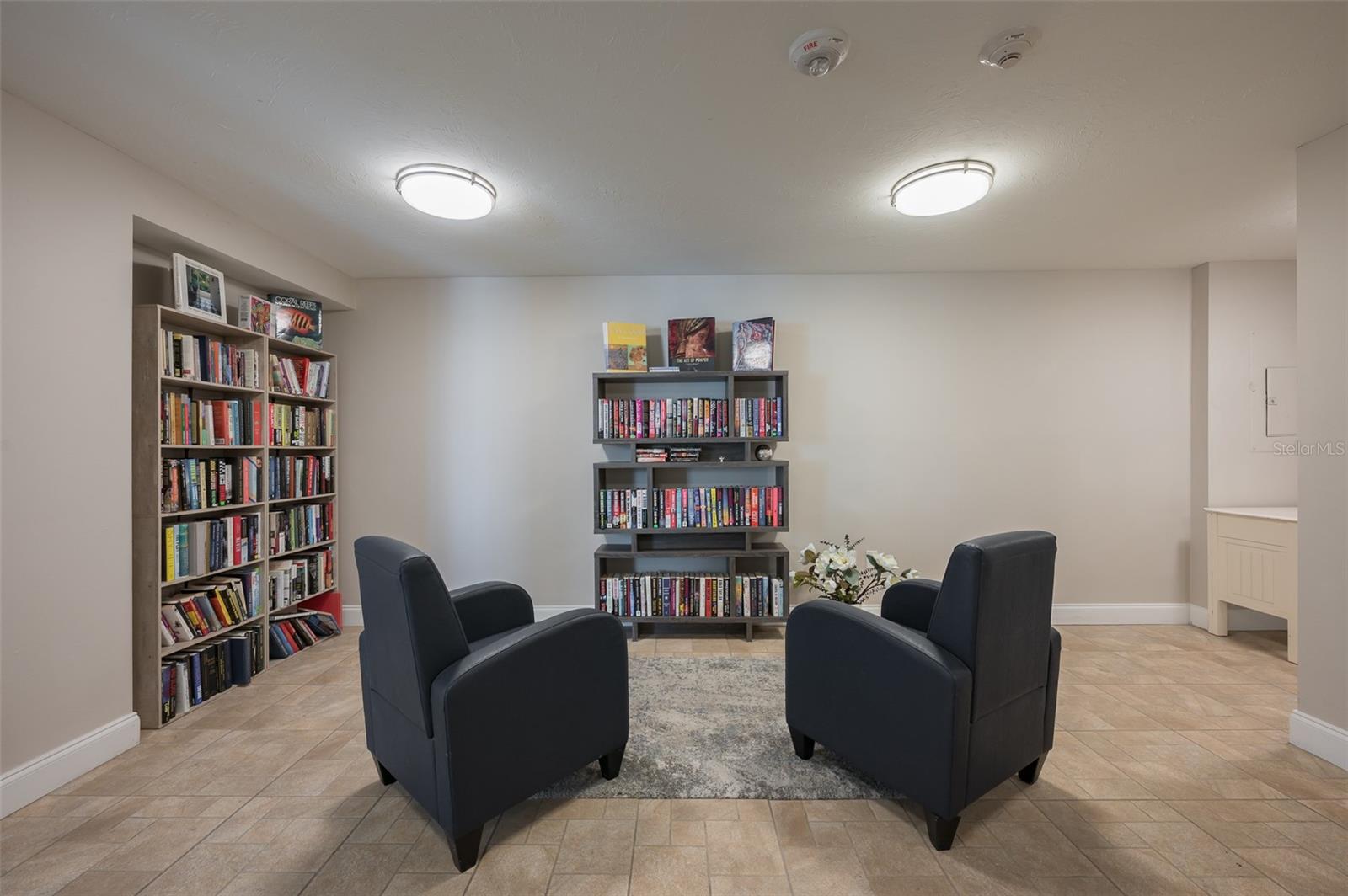 Reading room with book-filled shelves and two dark armchairs facing each other.