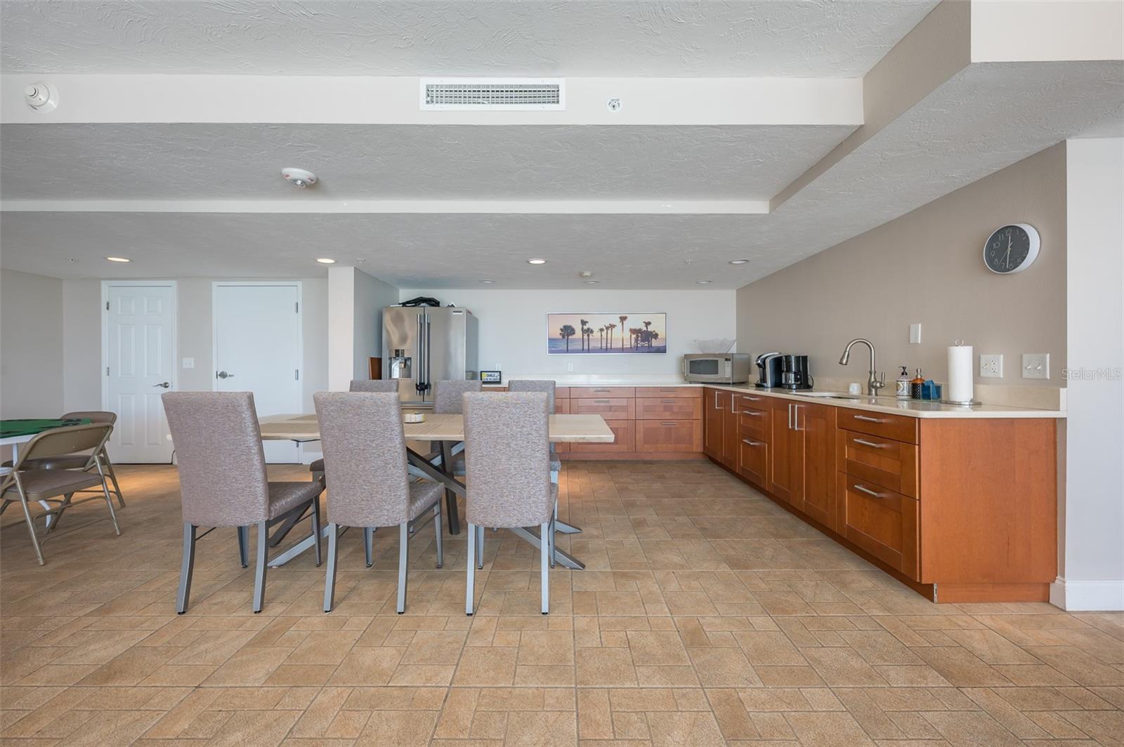 Kitchen and dining area with wood cabinets, stainless steel refrigerator, tiled floors, and an upholstered dining set.