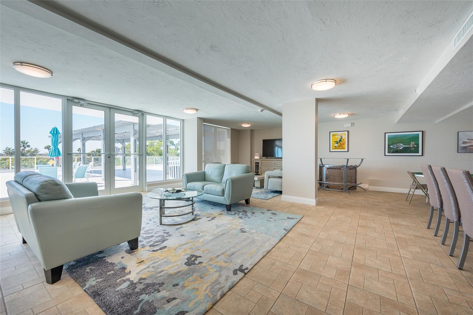 Condo living room with pale blue seating and glass doors opening onto a sunny terrace.