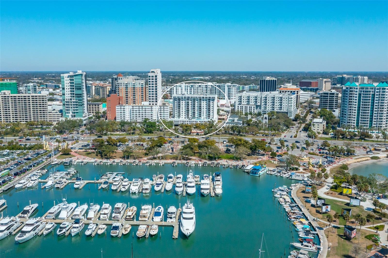Aerial view of downtown Sarasota and its marina, with a condominium building circled among the skyline.