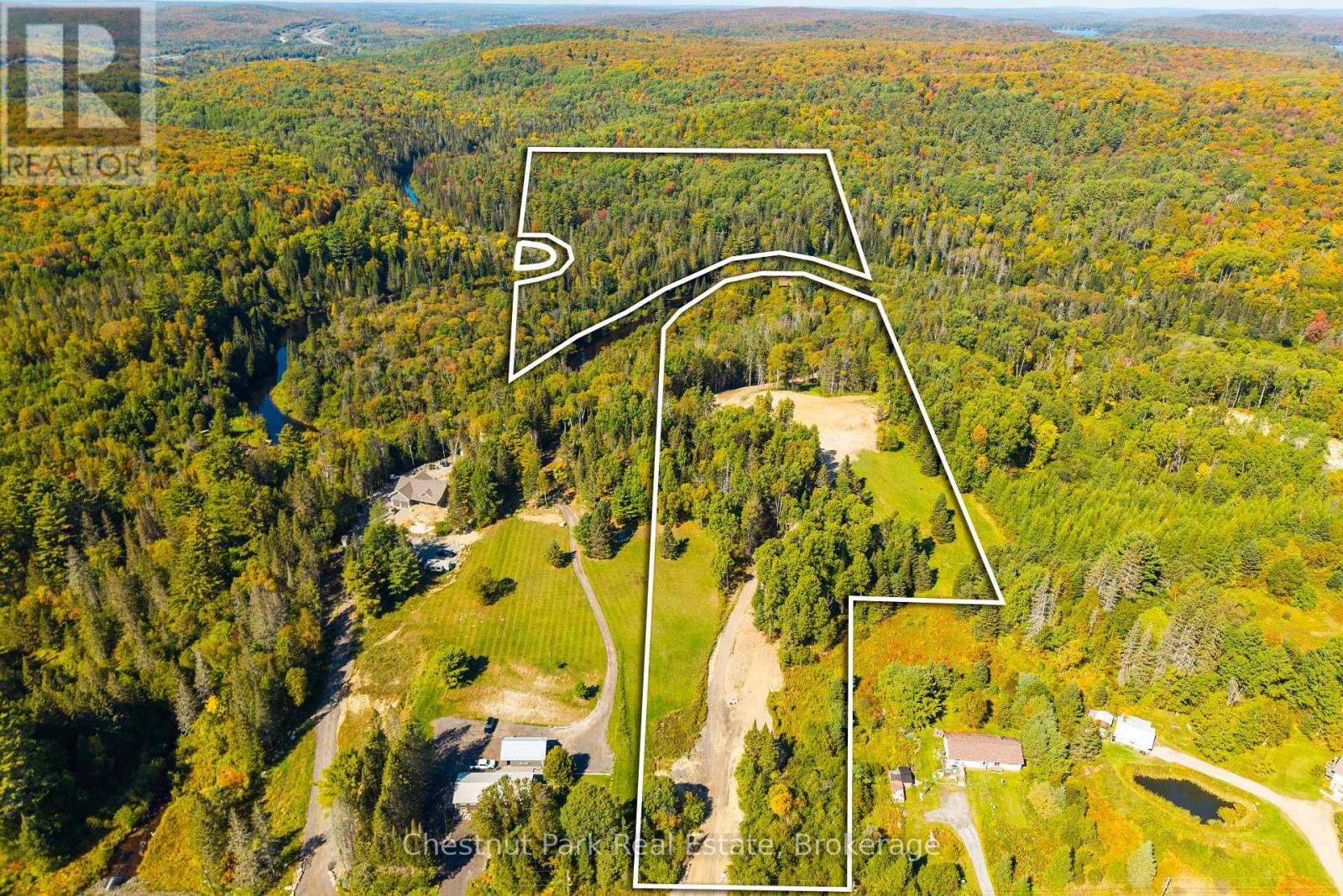 Aerial view of a large forested parcel outlined in white, with open clearings and a winding access road.