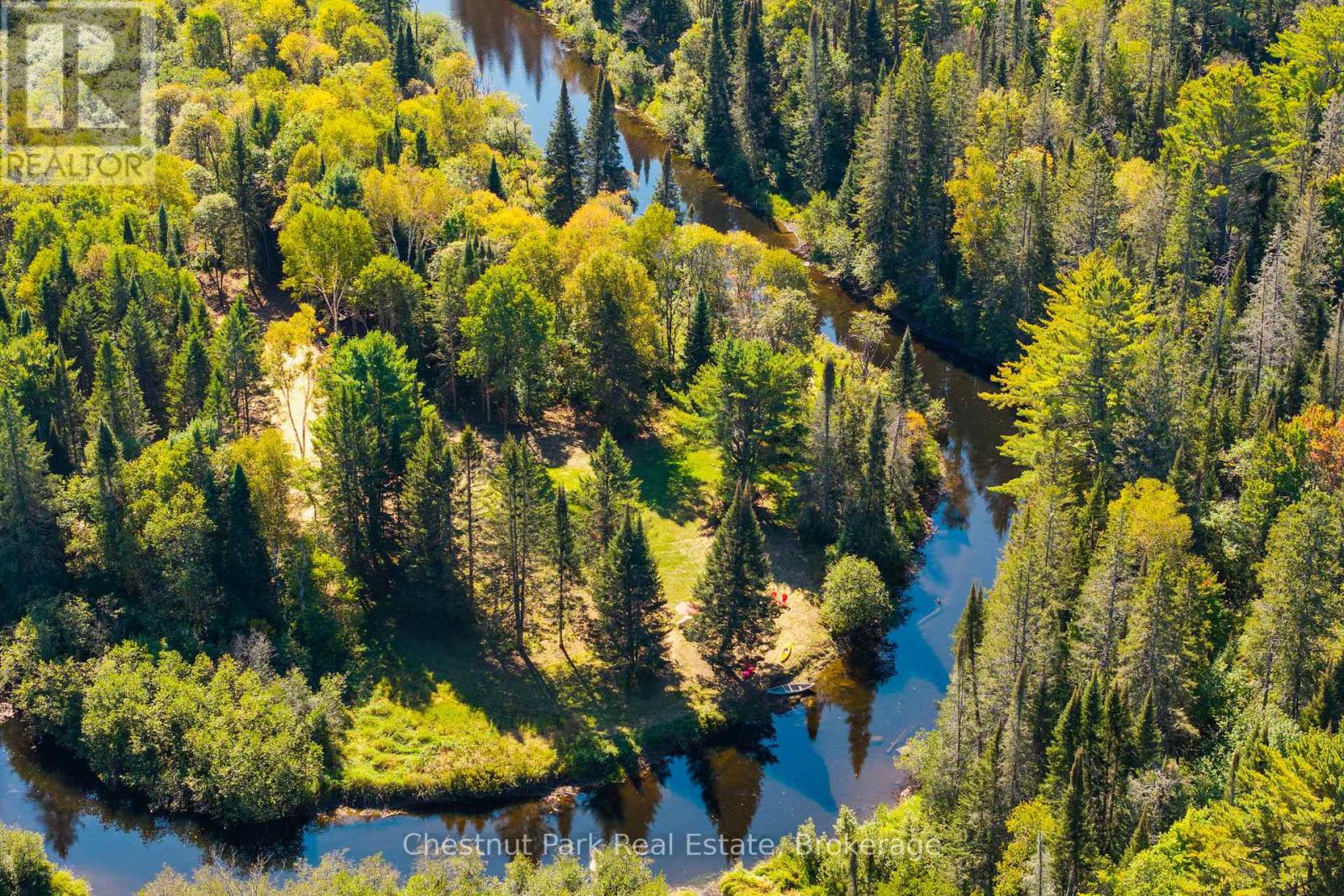 A wooded property bordered by a winding river, with a sunny clearing.