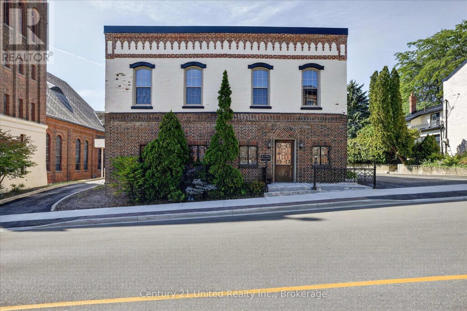 Historic brick building with a white upper facade and decorative brickwork along a Port Hope street.