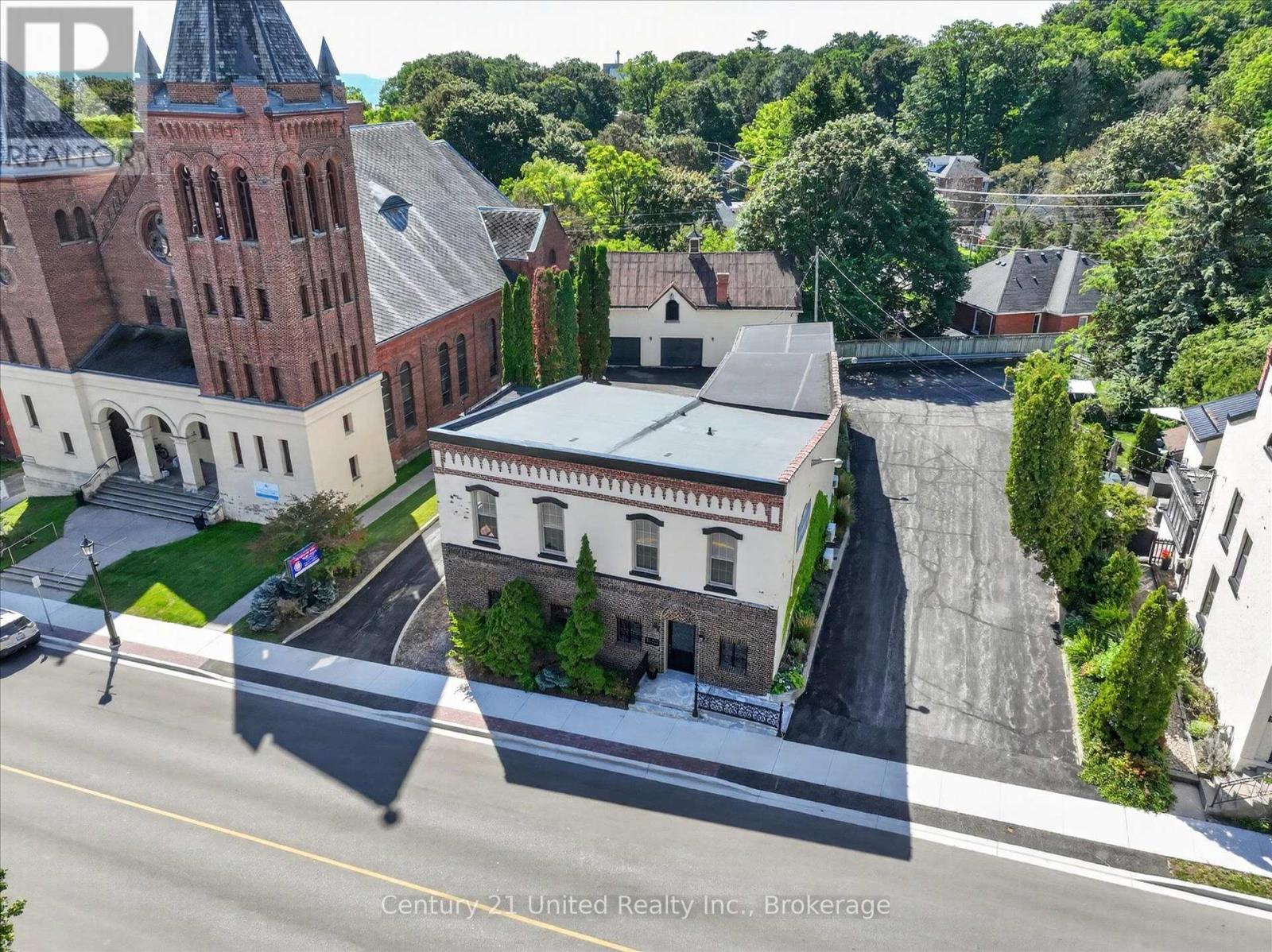 Aerial view of a two-storey brick-and-white commercial building beside a large red-brick church.