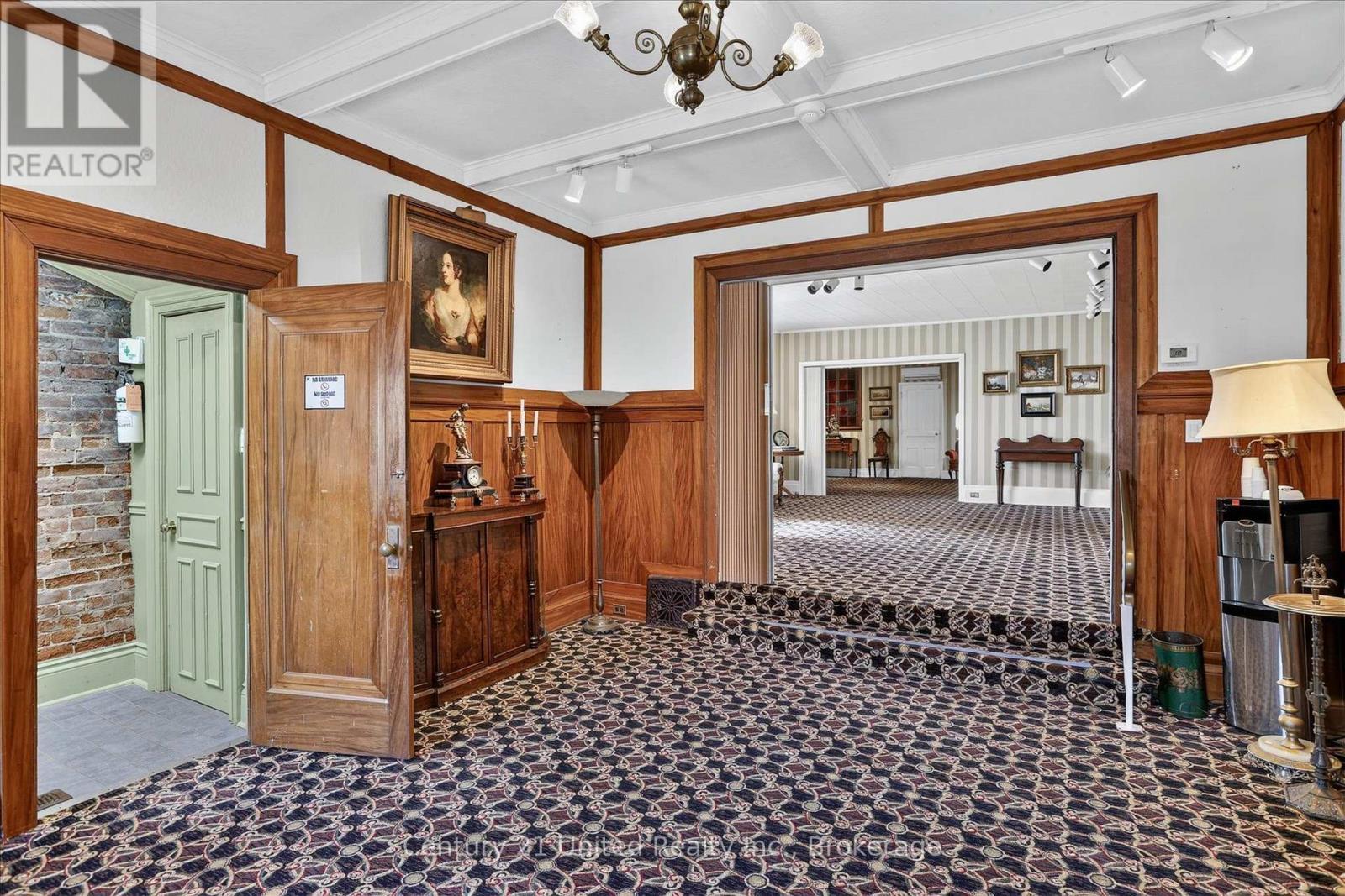 Entry hall with patterned carpet, wood paneling, and open doorways to adjoining rooms.