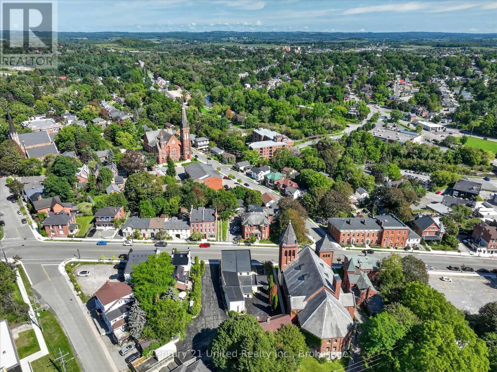 Aerial view of a leafy town center with a red-brick church and tall steeple.