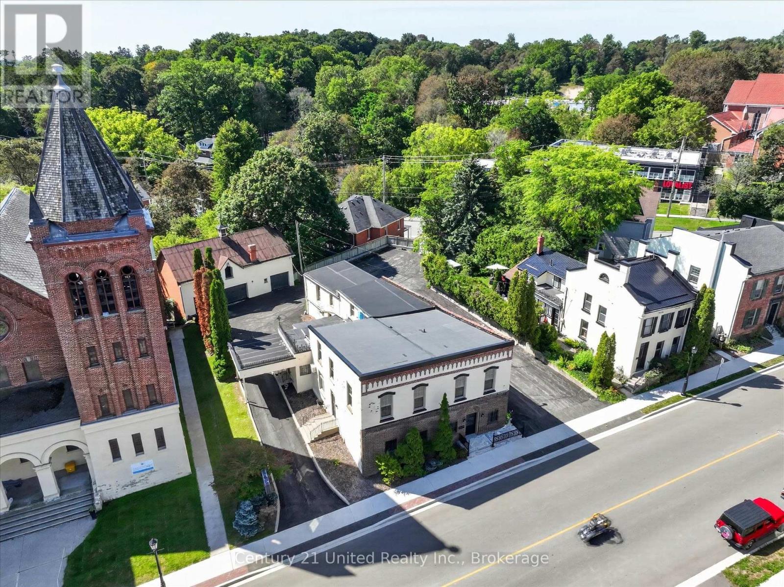 Aerial view of a downtown property beside a brick church, surrounded by historic buildings and trees.
