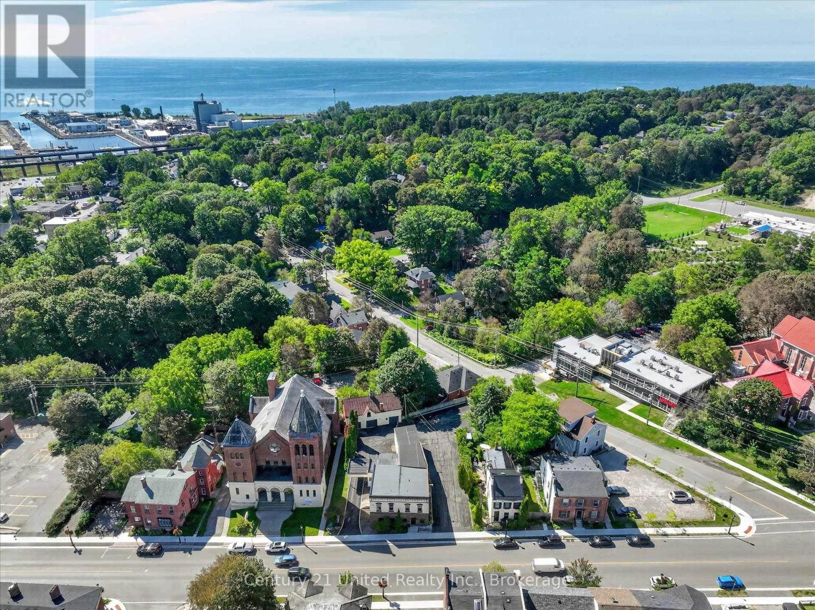 Aerial view of Port Hope with leafy streets, a prominent church, and Lake Ontario beyond.