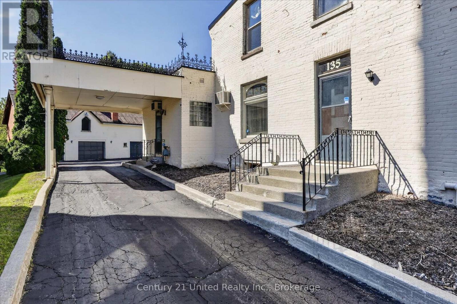 White brick building at 135 Walton Street with a covered driveway and railed entrance steps.