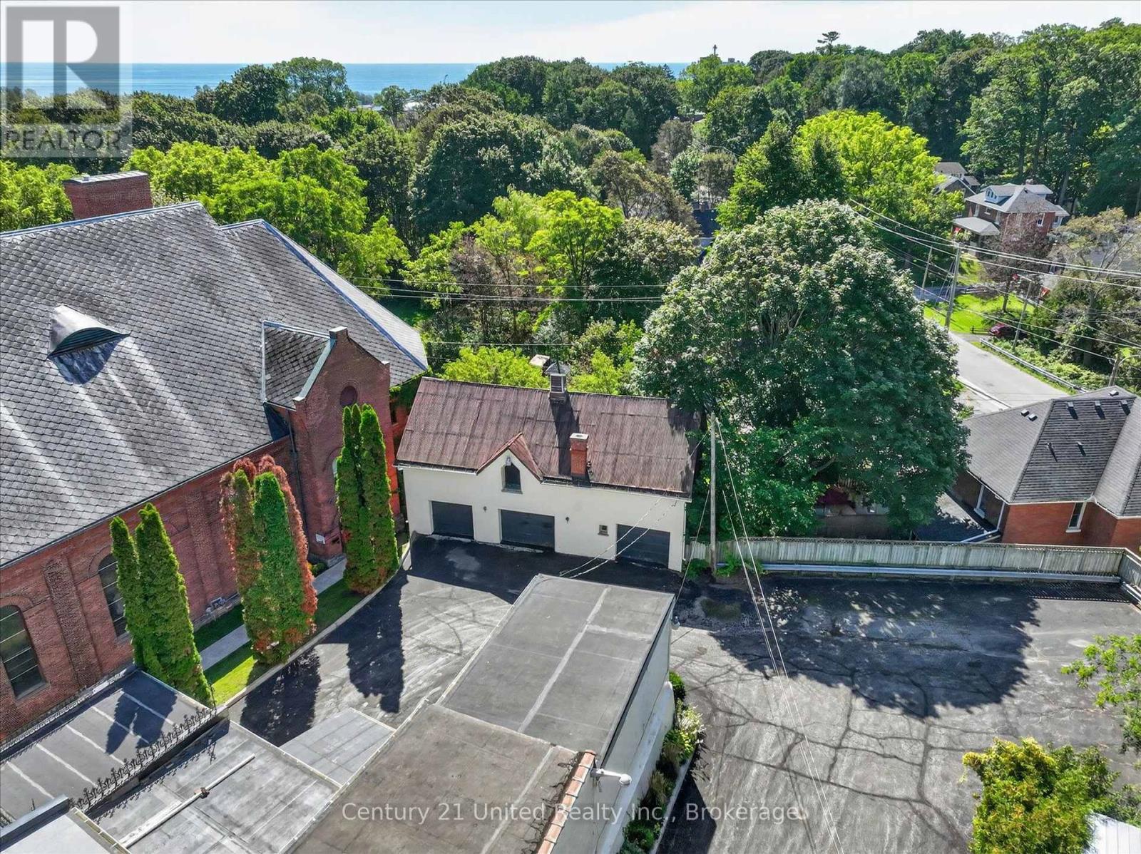 Aerial view of buildings and parking areas among trees, with water visible in the distance.