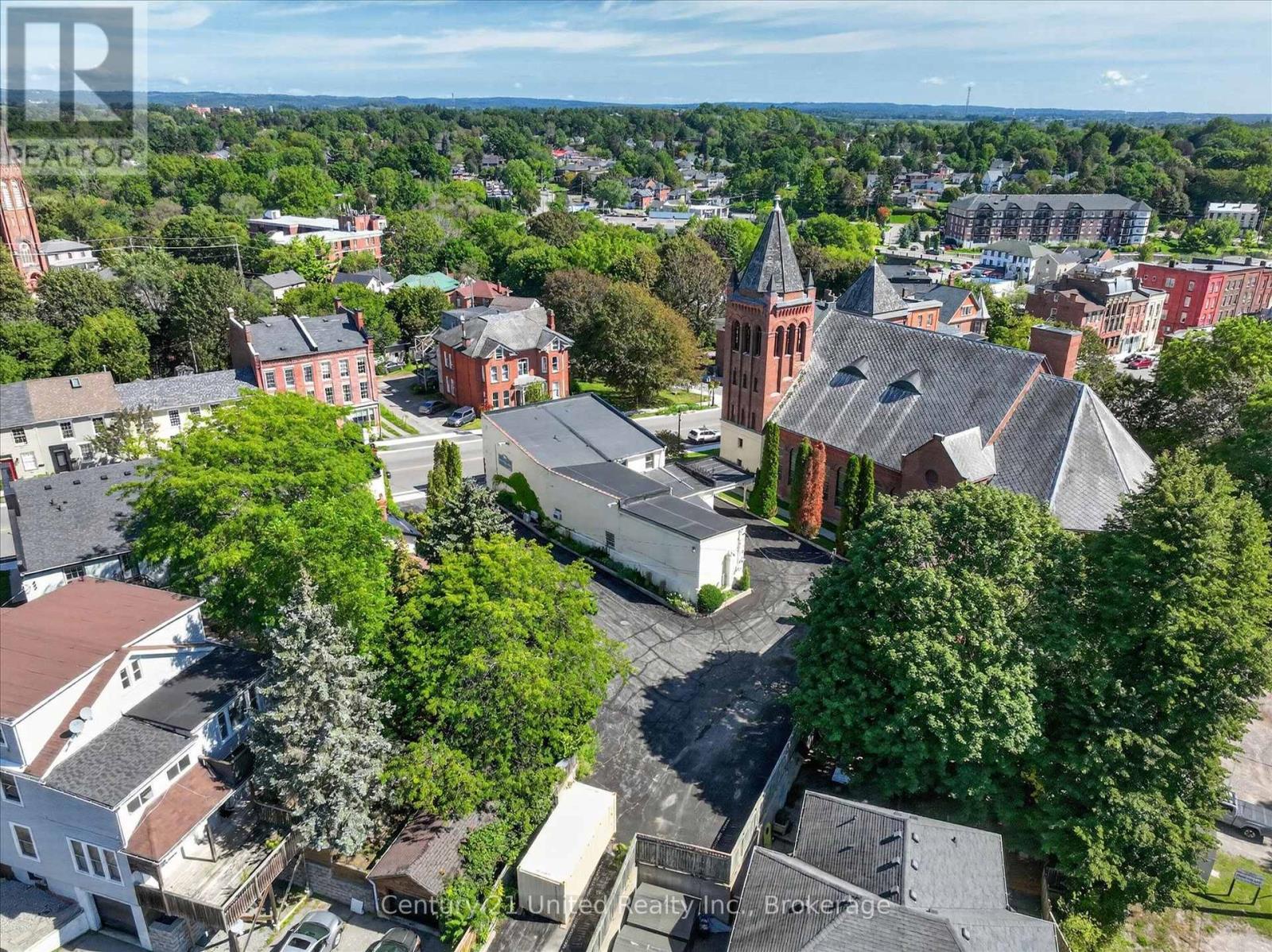 Aerial town view with a red-brick church surrounded by leafy streets and older buildings.