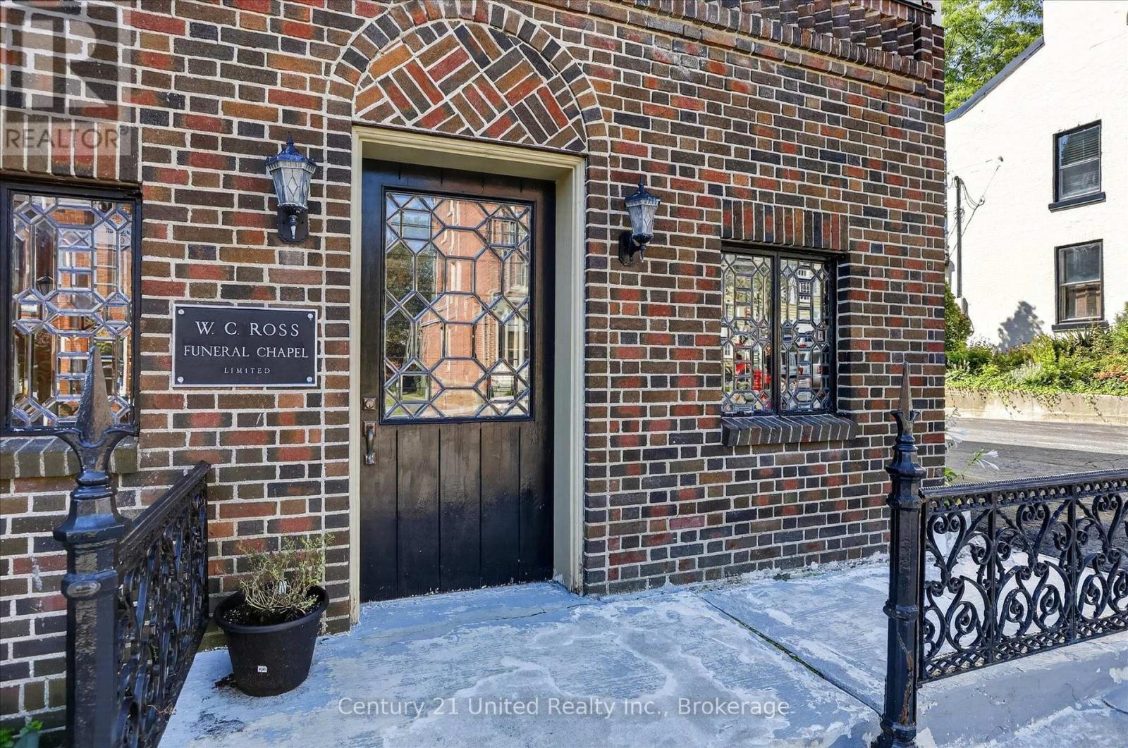 Brick funeral chapel entrance with a decorative glass door, leaded-glass windows, and ornate iron railings.