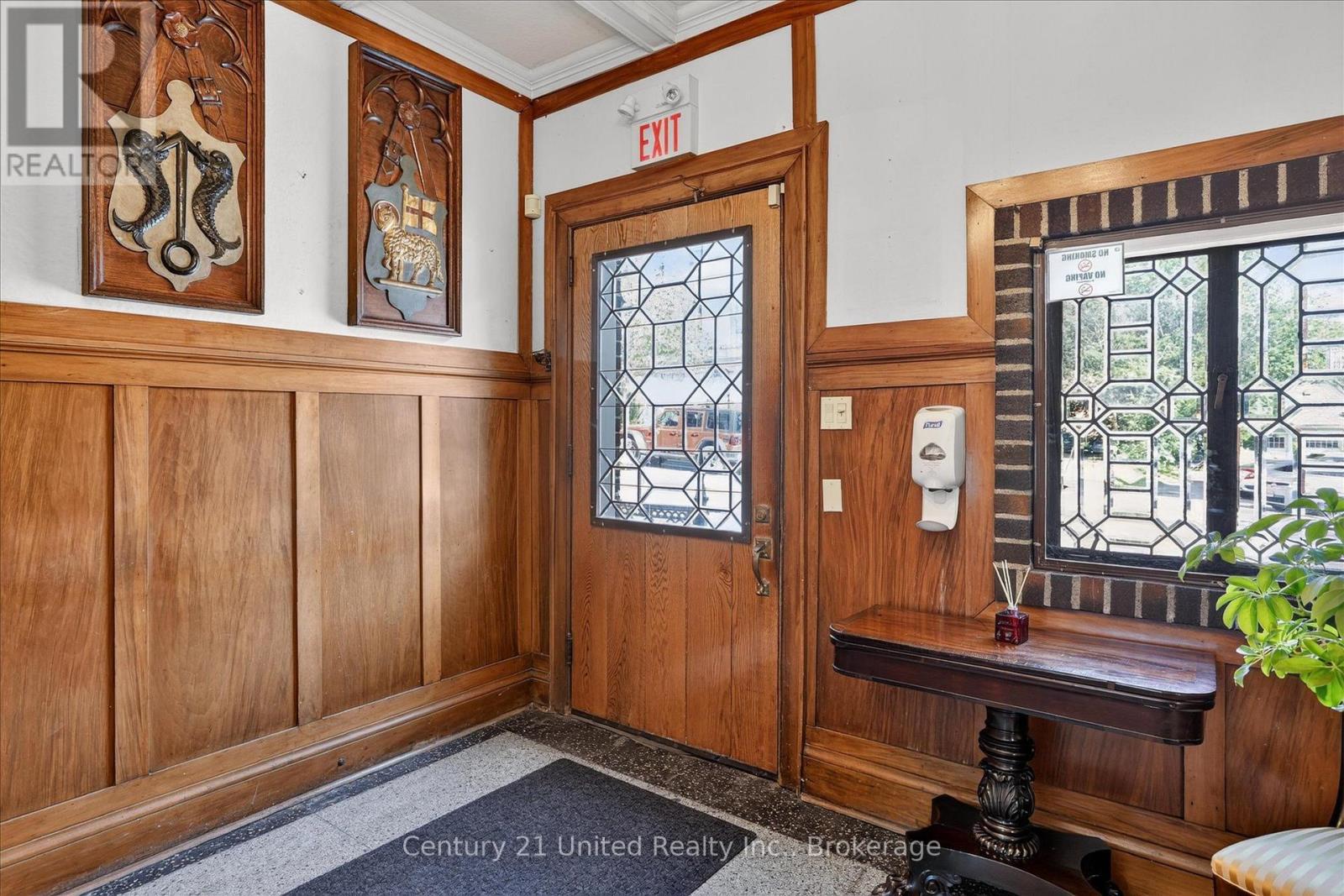 Wood-paneled entry foyer with carved plaques, a leaded-glass front door, and matching window.