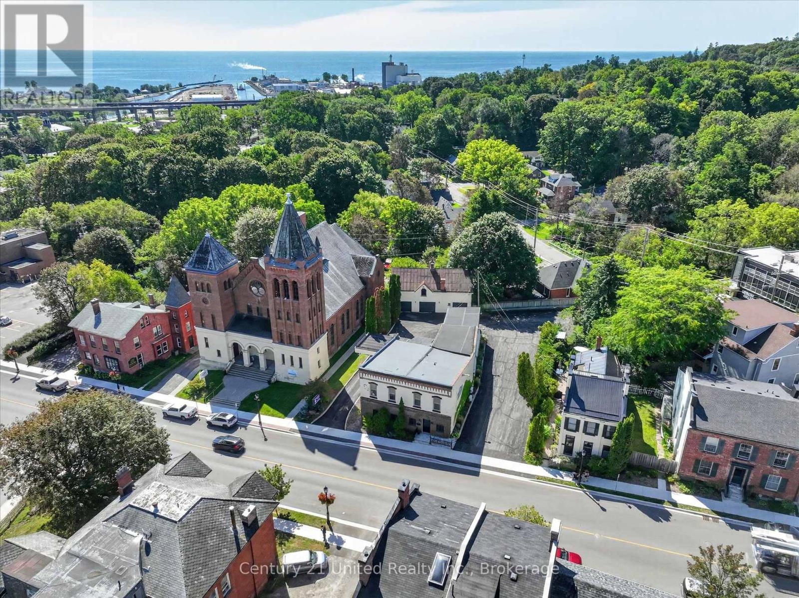 Aerial view of Port Hope’s downtown, with a red-brick church, leafy streets, and Lake Ontario beyond.