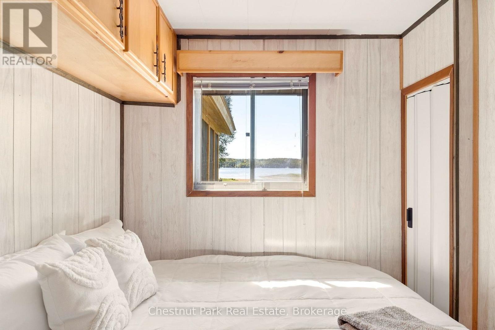 Bedroom with a white bed and a window overlooking the lake.