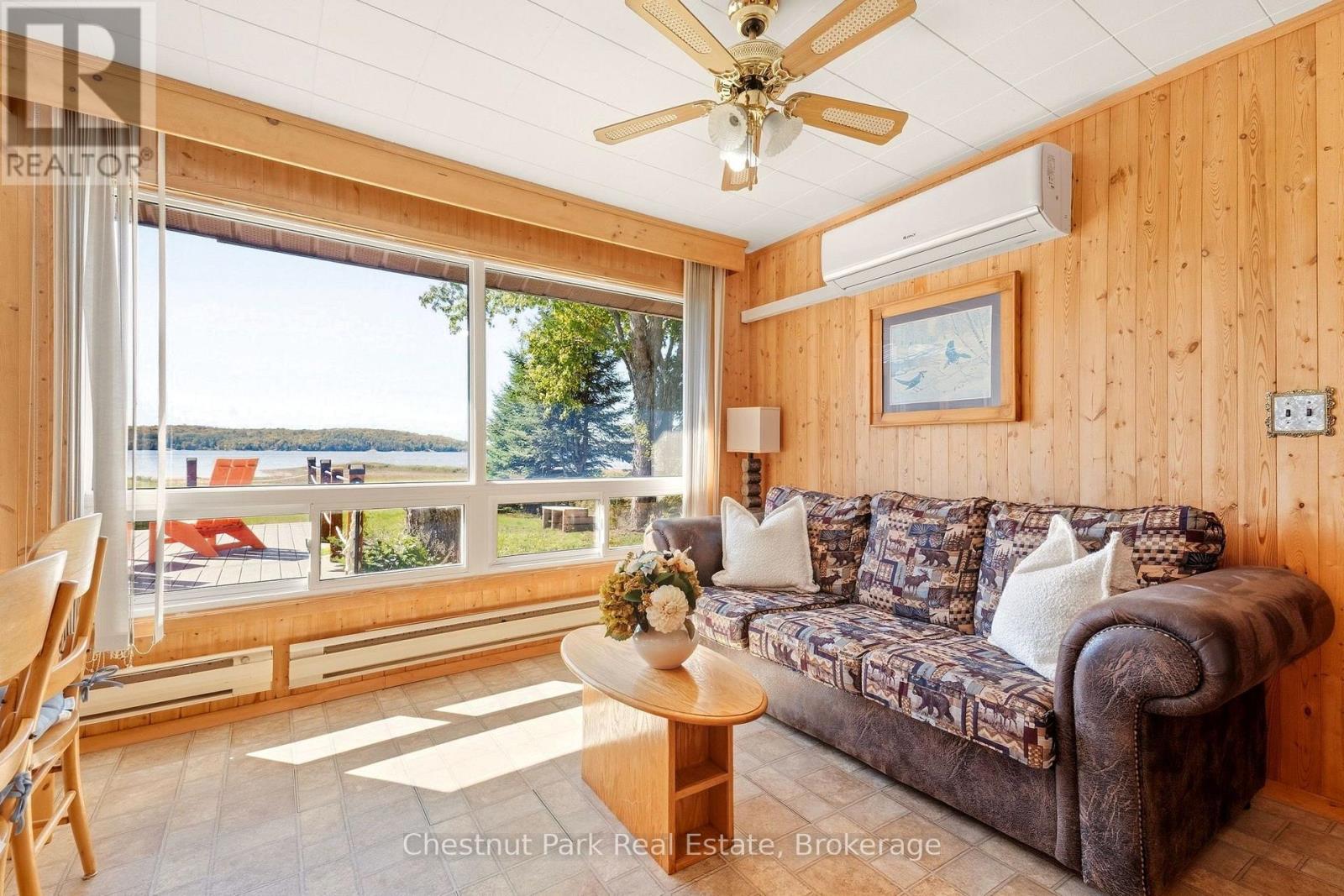 Living room with wood-paneled walls and large windows overlooking a lake.