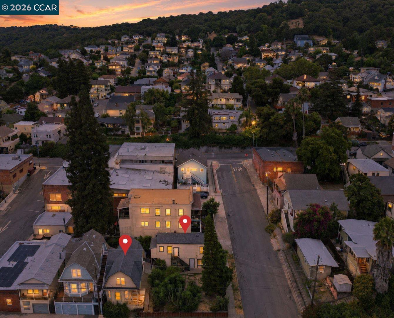 Aerial view of a hillside neighborhood at sunset, with homes and two listing pins.