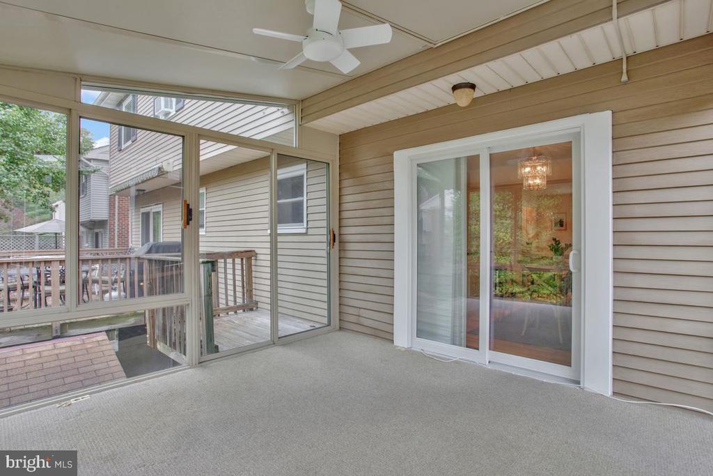 Enclosed porch with screened windows, beige carpet, ceiling fan, and sliding glass door.