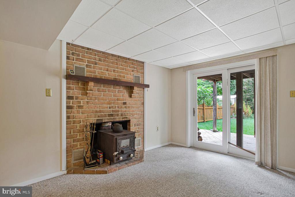 Unfurnished living room with a brick fireplace and wood stove beside sliding doors to the patio.