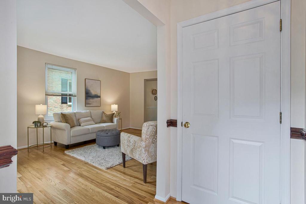 Staged living room with a white sofa, hardwood floors, and a large paneled entry door.