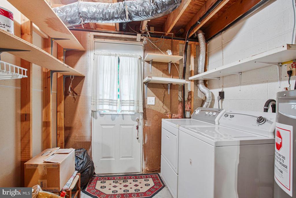 Laundry room with white washer and dryer, exposed ductwork, and open wooden shelving.