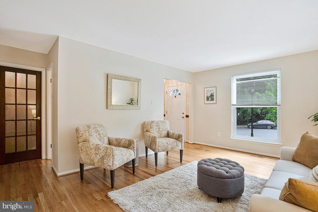 Living room with patterned armchairs, hardwood floors, and a large street-facing window.