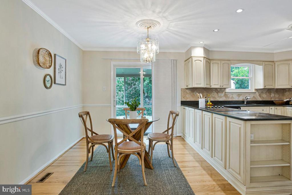 Kitchen and dining area with cream cabinets, a round table, and a sliding glass door to greenery.