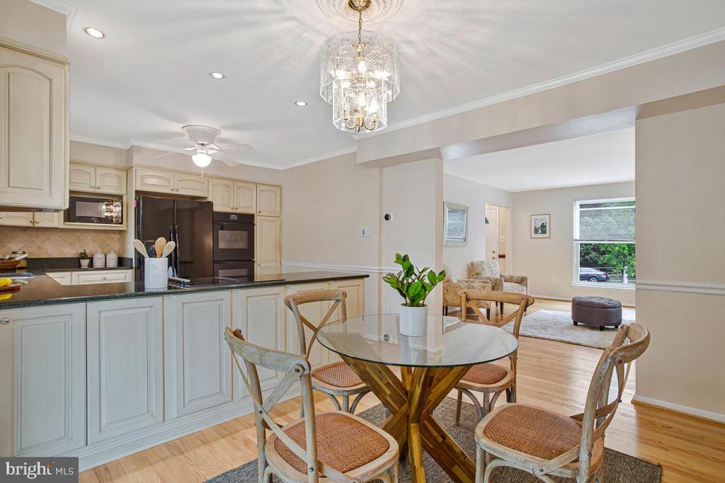 Kitchen and dining area with cream cabinetry, a glass-top table, and an adjoining sitting area.