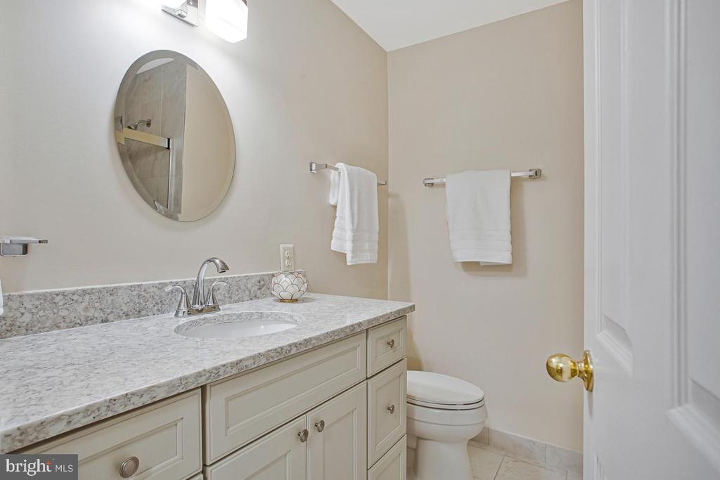 Bathroom with a stone-look vanity, round mirror, white towels, and toilet.