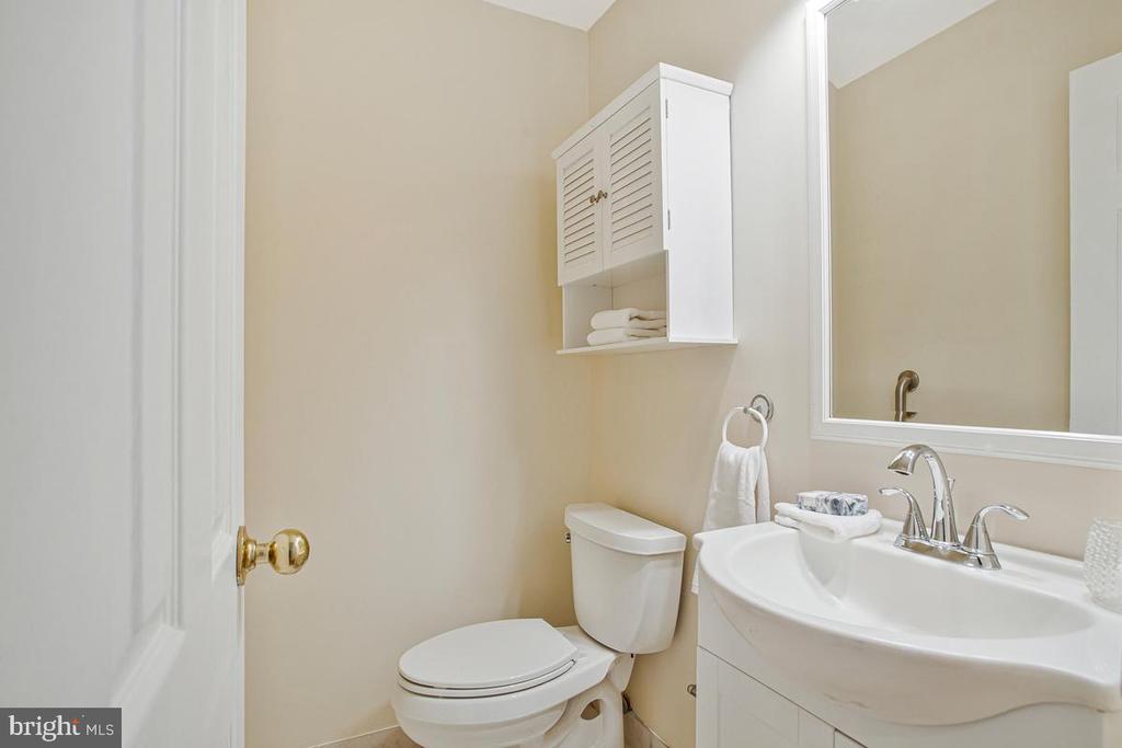 Bathroom with a white vanity, chrome faucets, large mirror, and wall-mounted cabinet.