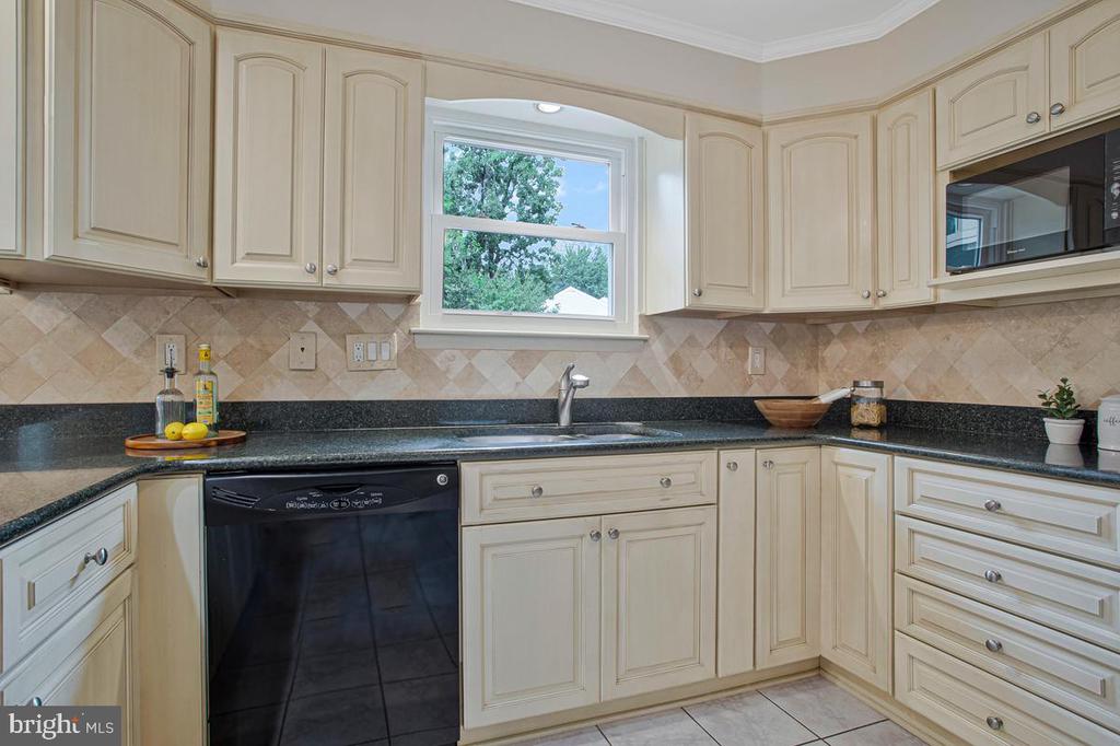 Kitchen with cream cabinetry, black granite counters, and a window above the sink.
