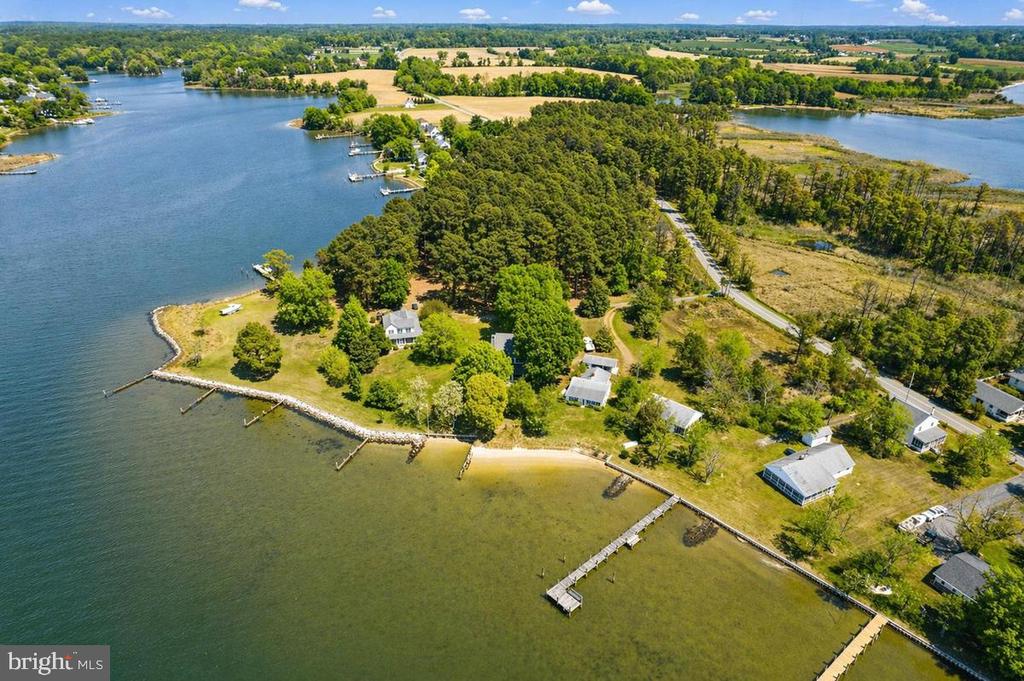 Aerial view of a wooded waterfront property with several houses and piers along the inlet.