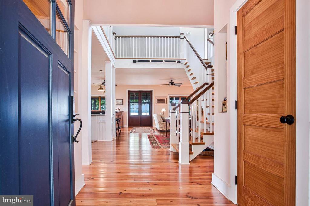 Entry foyer with polished hardwood floors, a staircase, and an open dark blue front door.