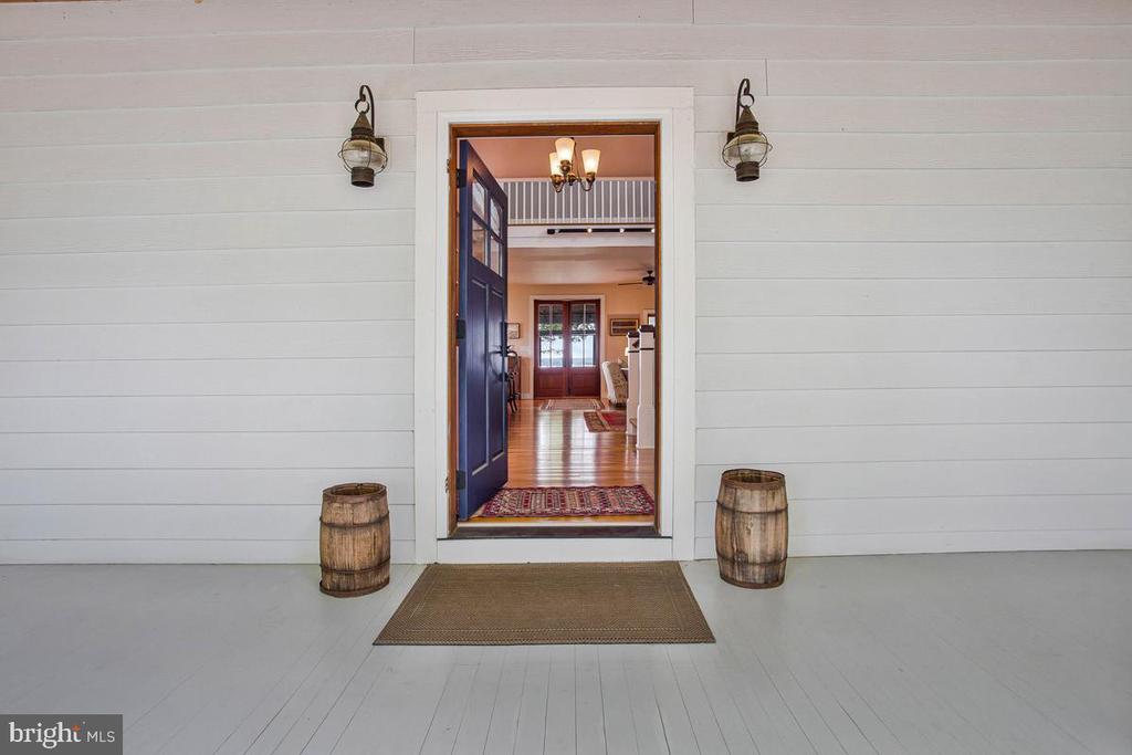 Home entrance with an open blue door, paired lanterns and wooden barrels on the porch.
