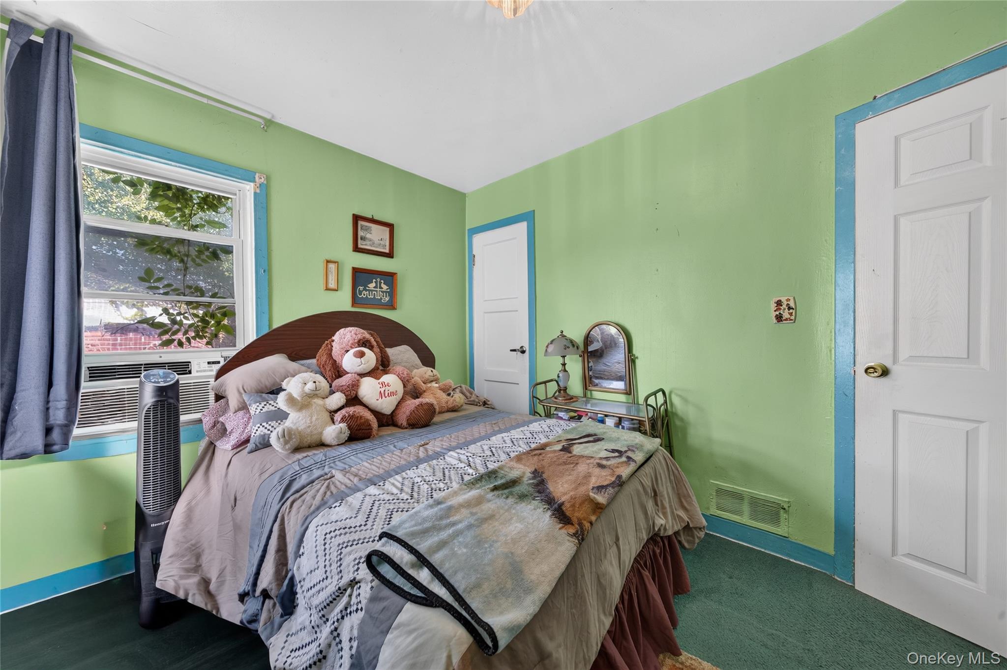 Bedroom with green walls, blue trim, and stuffed bears arranged on the bed.