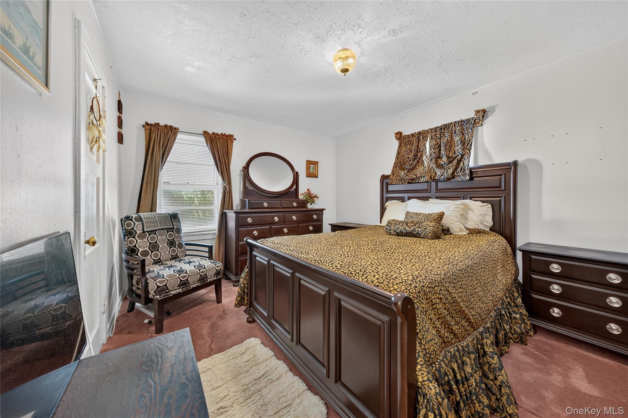 Bedroom with dark wood furniture, animal-print bedding, and a patterned armchair.