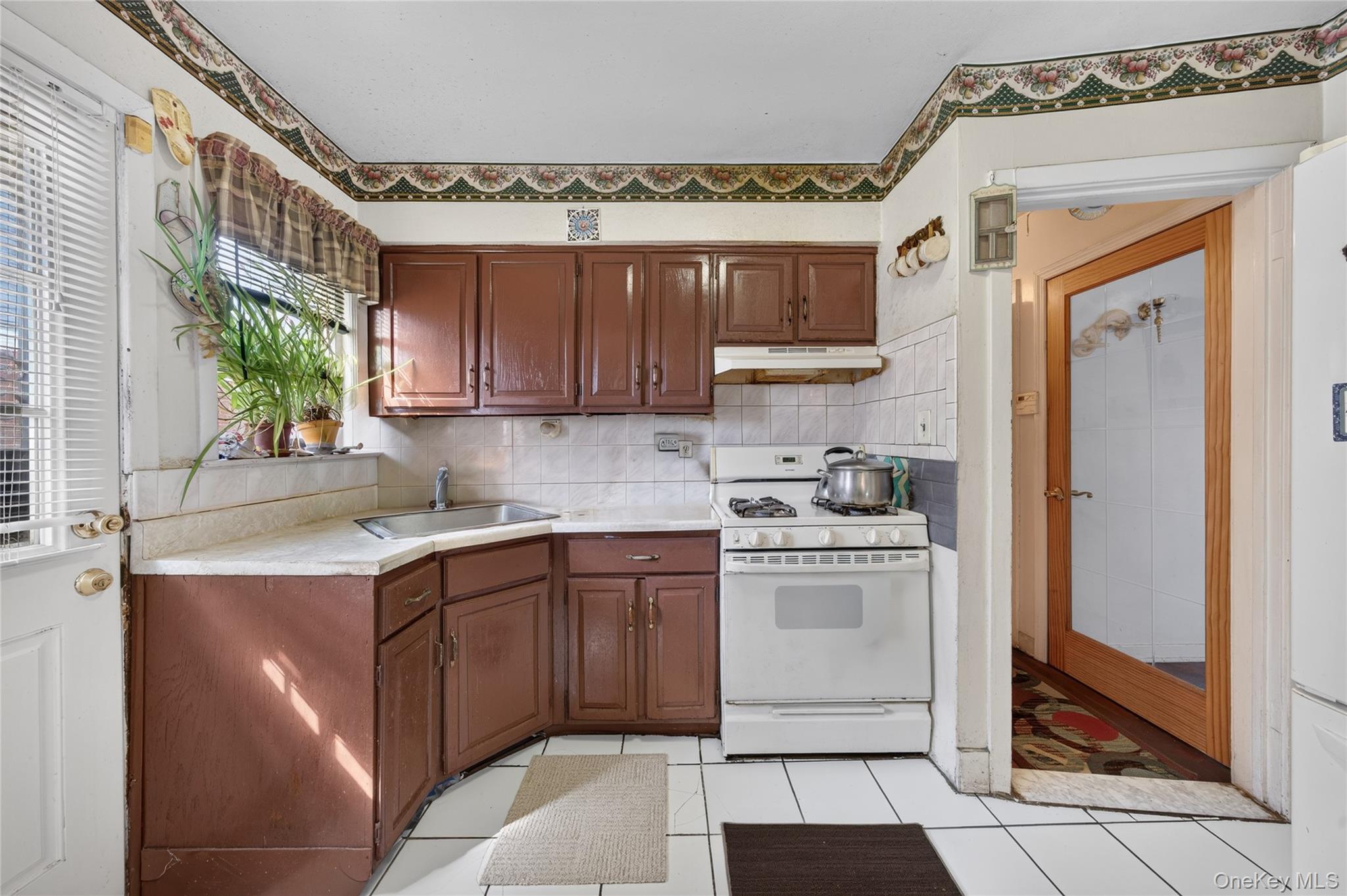 Kitchen with dark brown cabinets, white tile counters, and a freestanding gas range.