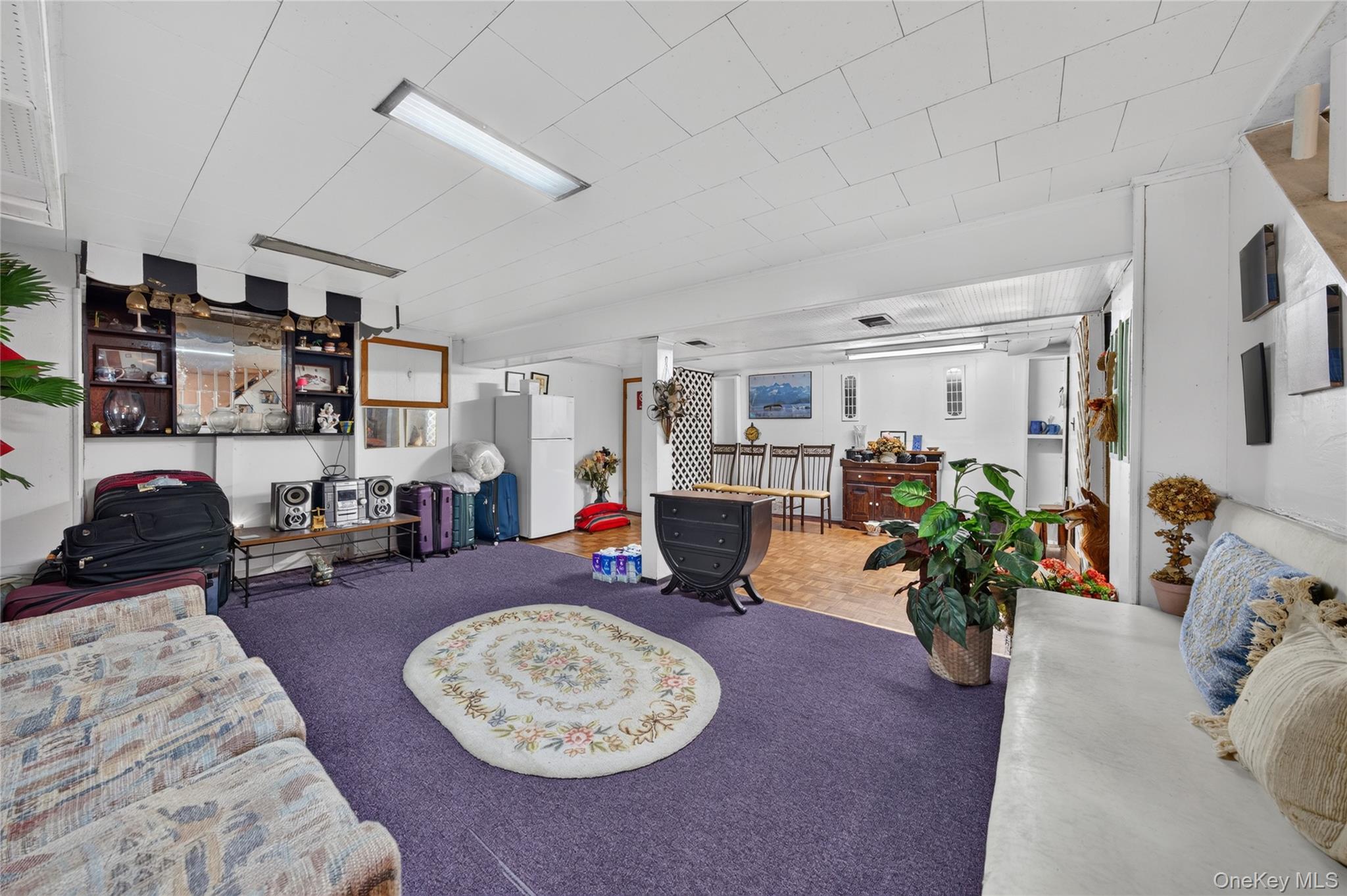 Furnished basement recreation room with purple carpet, a floral rug, sofas, and a foosball table.