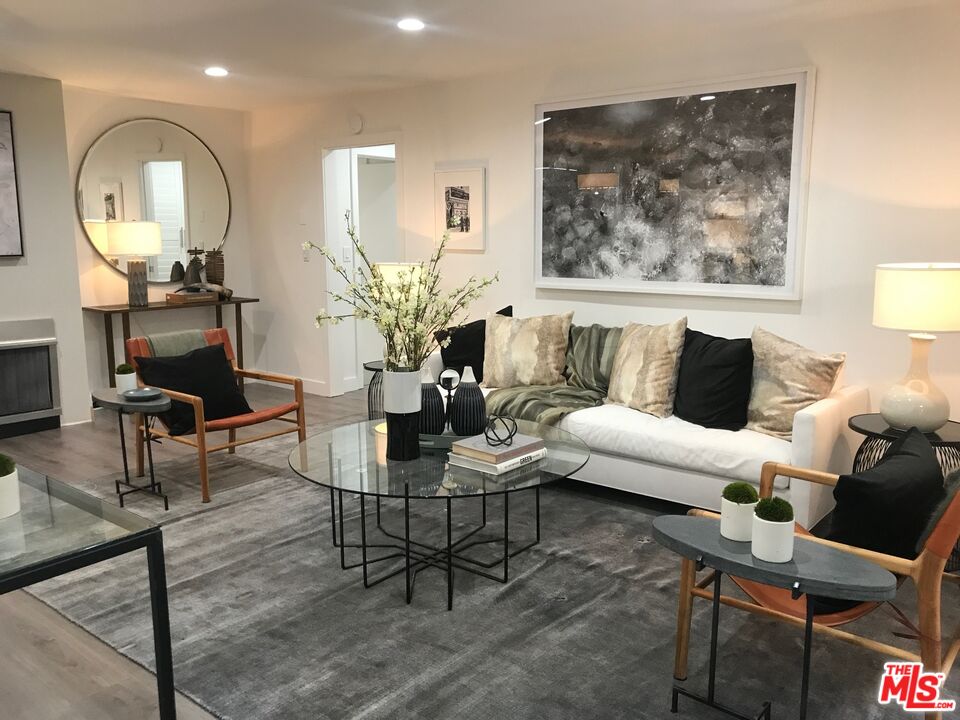 Staged living room with a white sofa, glass coffee table, and large abstract wall art.